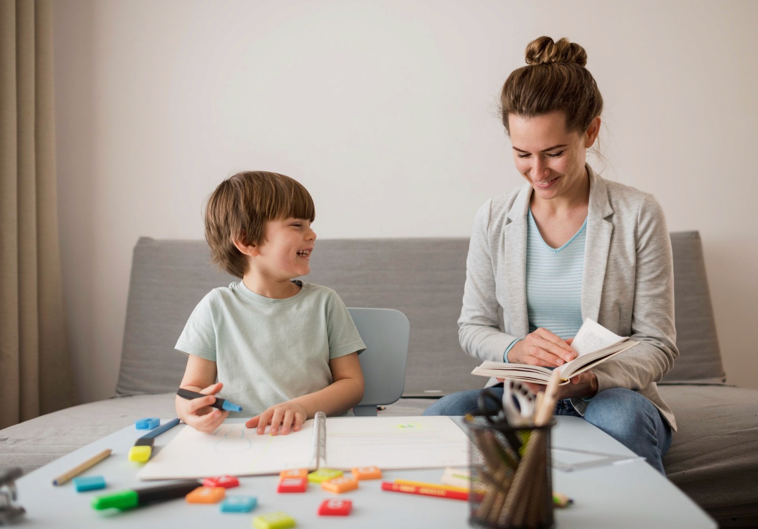 A BCBA reading with a child at a desk.